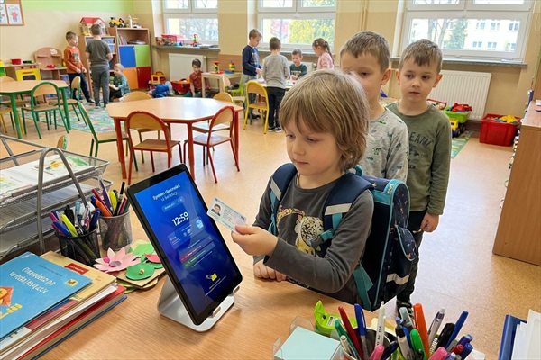 Krok 1 — dziecko przykłada kartę do terminala w świetlicy, w kolejce czekają kolejni uczniowie