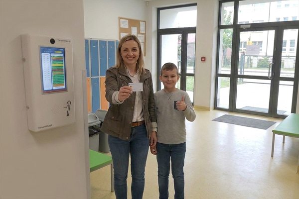 Osoba odbierająca z kartą zbliżeniową i odebrane dziecko przy terminalu e-Świetlicy w przedsionku szkoły